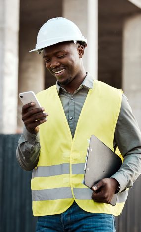 Shot of a young businessman using his smartphone while on a construction site.
